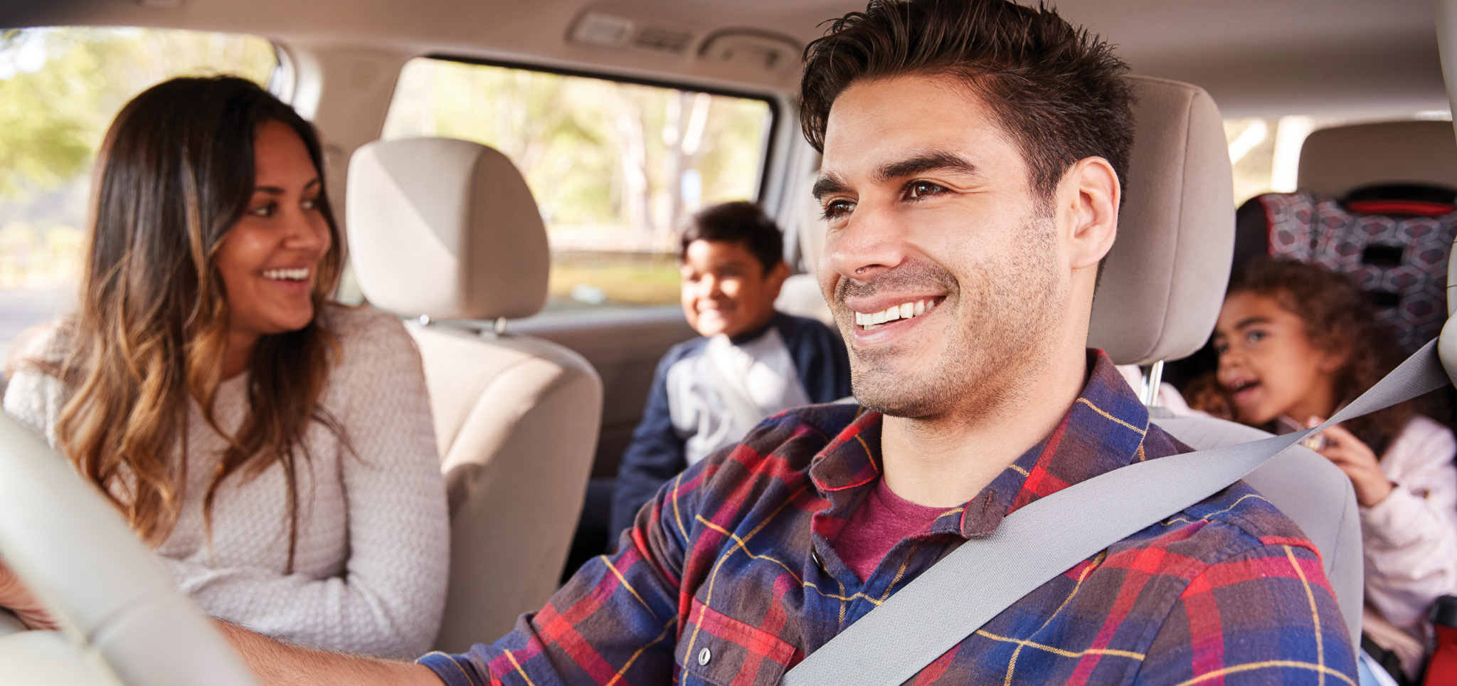 A happy family of four, smiling in the car.