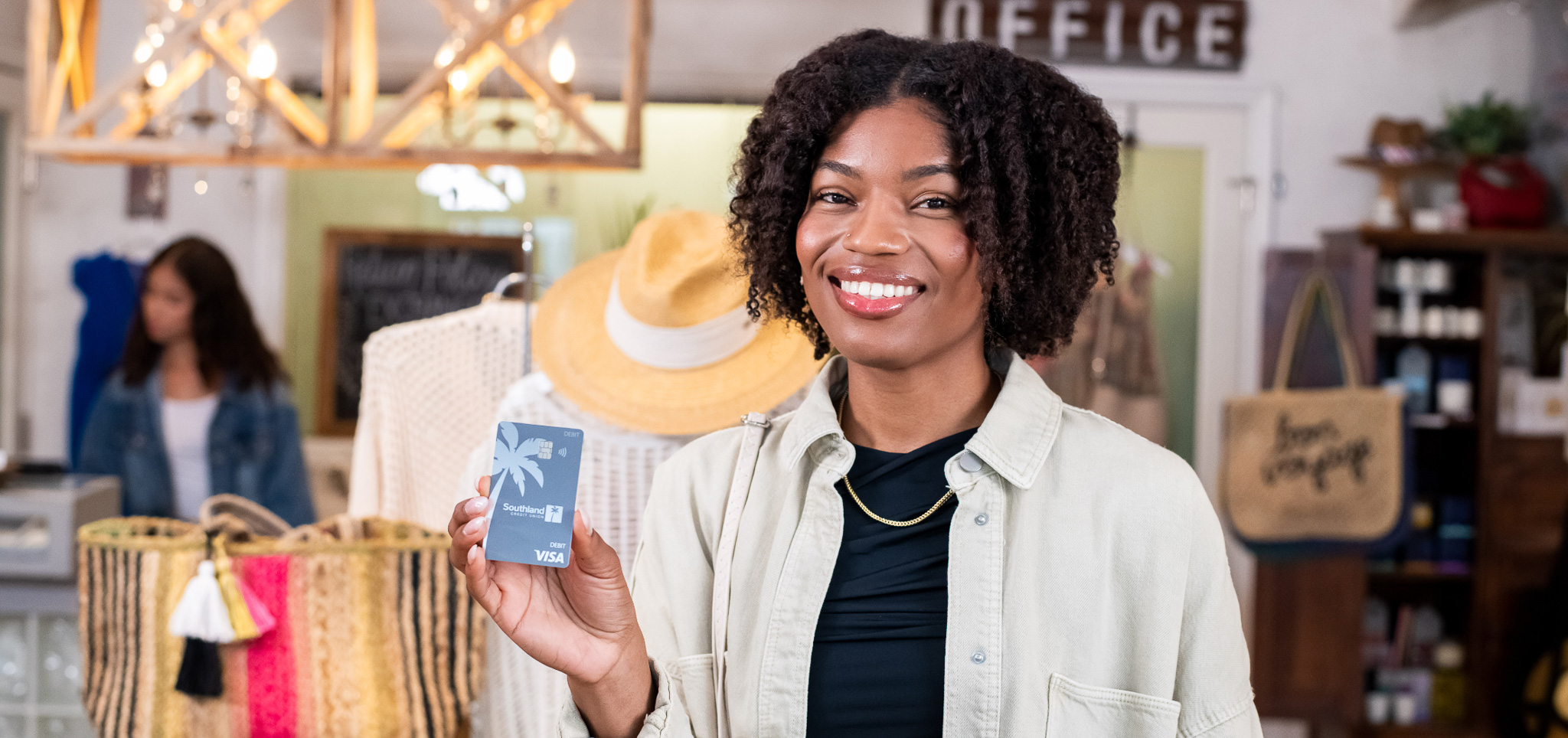 A woman smiling and holding a Southland Enjoy! Rewards debit card.