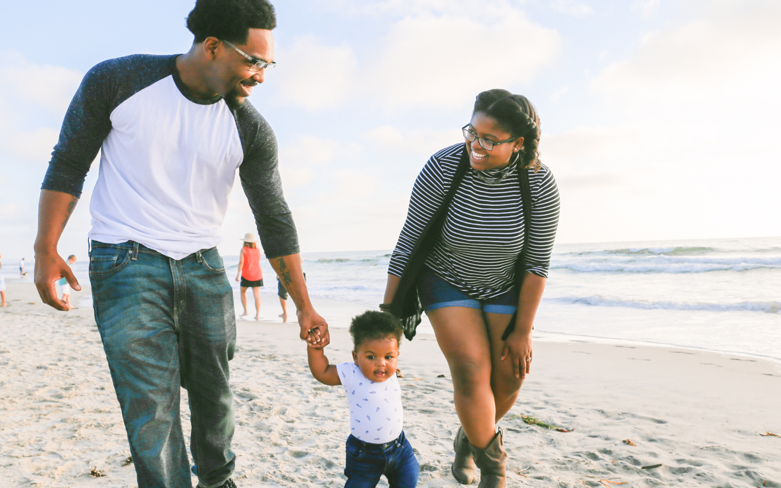 Young mom and dad walking son on the beach