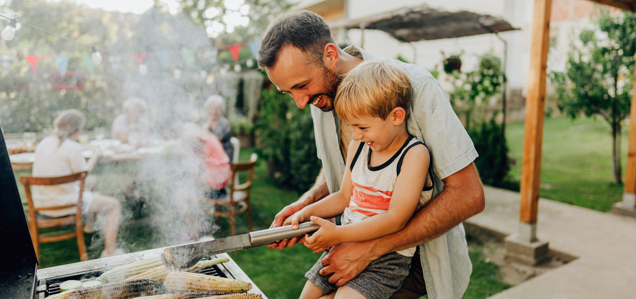 Father and son smiling and barbecuing together.