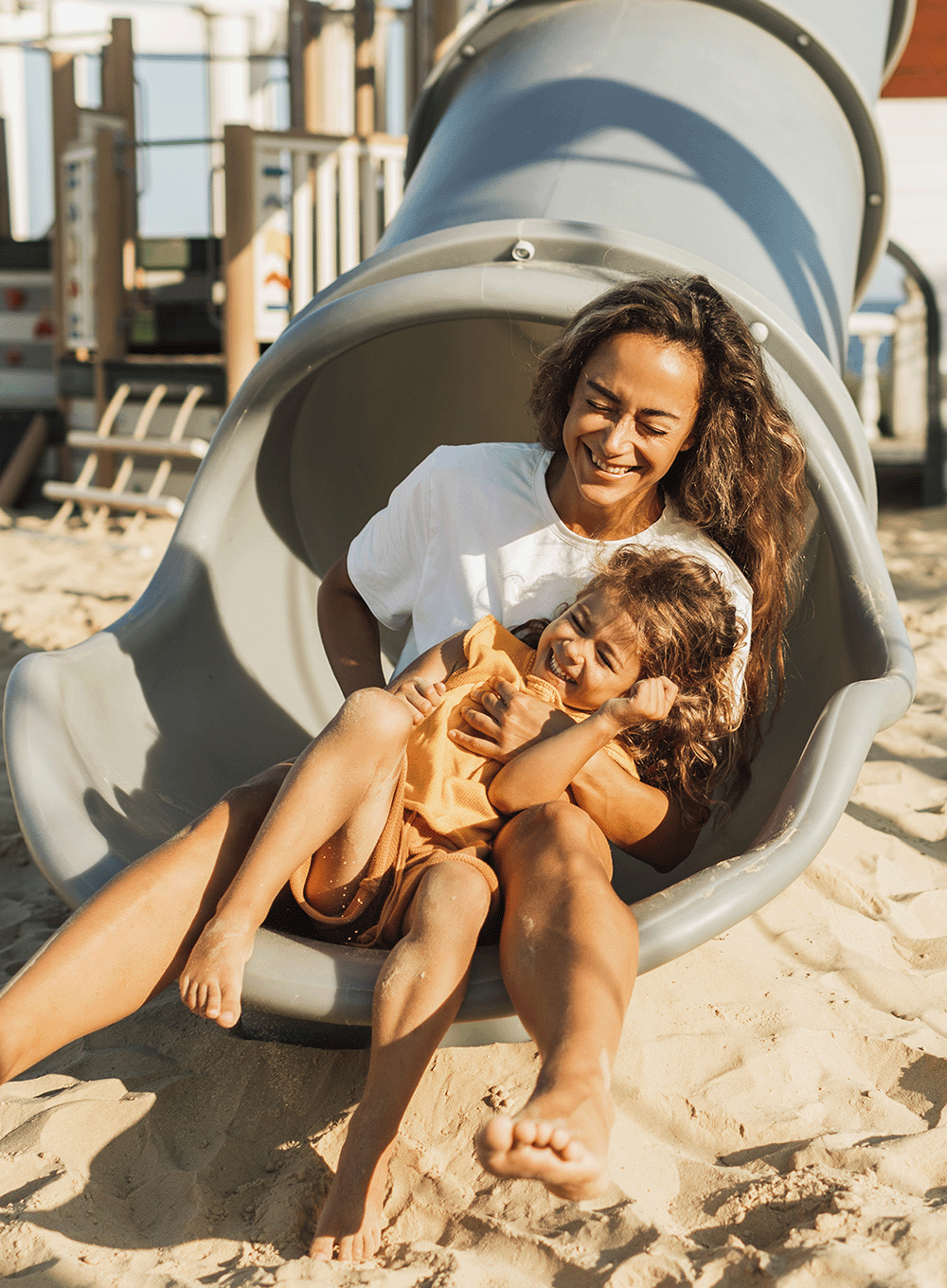 Mother and daughter going down a slide at the playground