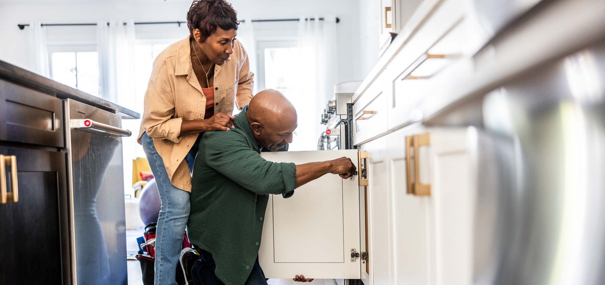 A couple working together while fixing a cabinet