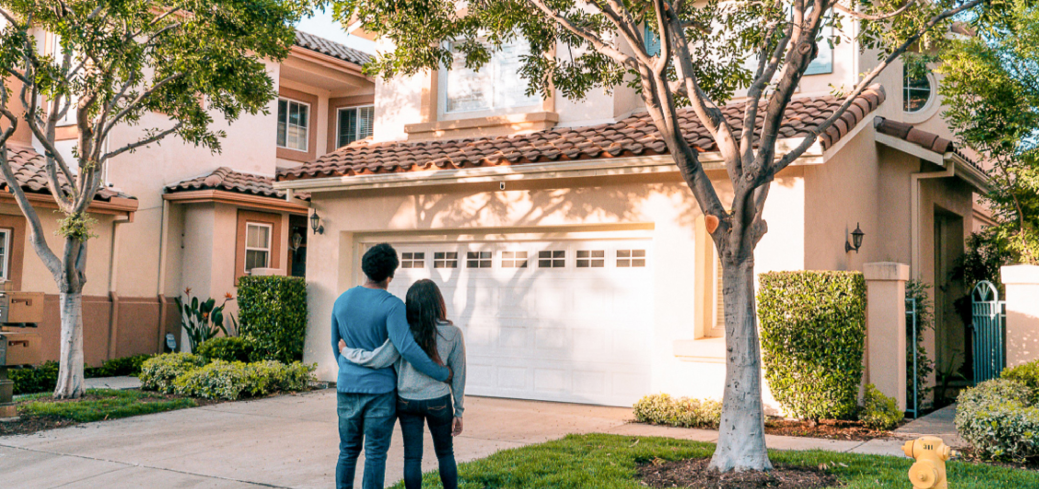 A couple standing together looking at a house.